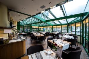 Studios Astra Hotel Vevey في فيفي: مطعم بطاولات وكراسي ونوافذ