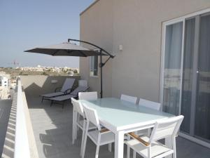 uma mesa e cadeiras numa varanda com um guarda-sol em Blue Sky Apartments em Mġarr