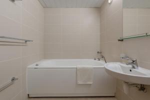 a white bathroom with a sink and a bath tub at Raadimõisa Hotell in Tartu