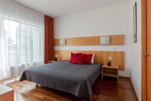 Un dormitorio con una cama con almohadas rojas y una ventana en Raadimõisa Hotell, en Tartu