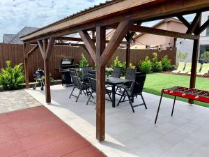 un patio con mesa y sillas bajo una pérgola de madera en Finfera Villa, en Balatonboglár