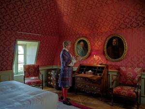 a woman standing in a red room with a bed at Relais & Château Louise de La Vallière in Reugny