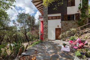 una casa con puerta roja y sillas rosas en Casa en Montseny con piscina, en Sant Pere de Vilamajor