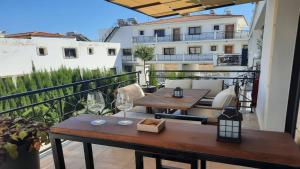 uma varanda com uma mesa de madeira e copos de vinho em Paramount Gardens Resorts C201 em Lárnaca