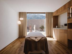 Cet appartement comprend une chambre avec un lit et une cuisine avec une fenêtre. dans l'établissement Lindenhof Pure Luxury & Spa DolceVita Resort, à Naturno