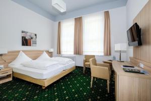 um quarto de hotel com uma cama, uma secretária e uma televisão em Hotel Brockenscheideck em Schierke