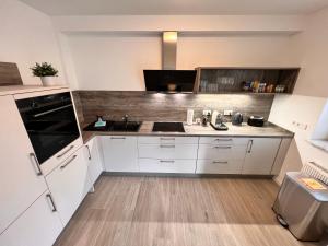 a kitchen with white cabinets and a black appliance at Veens Crew Home 4 Pax in Dreieich