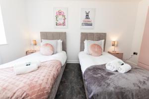 2 Betten in einem Zimmer mit weiß und rosa in der Unterkunft K Suites - Flat 114 Fulbridge Road in Peterborough