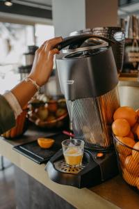 a person is making a cup of orange juice at Rocket Rooms Velden in Velden am Wörthersee