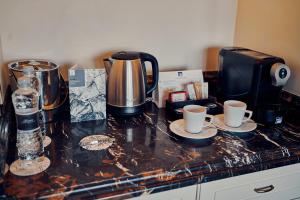 uma bancada com duas chávenas e uma cafeteira em Fairmont Grand Hotel Kyiv em Kiev