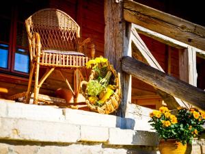 une chaise en osier et un panier de fleurs sur une terrasse couverte dans l'établissement Karkonoskie Siodło, à Kostrzyca