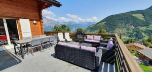 a balcony with chairs and tables and a view of mountains at Chalet le Fauconnier in La Tzoumaz