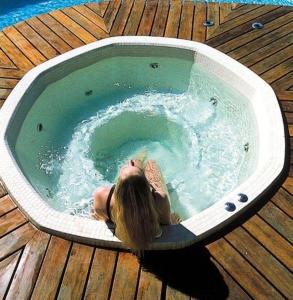uma mulher deitada num jacuzzi numa piscina em villa chez marie Meuble tourisme 3 etoiles em Sari Solenzara