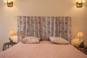a bedroom with a bed with two pillows and a curtain at Au coeur du Chat Perché in Arnay-le-Duc