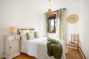 Habitación blanca con cama y ventana en Casa Rural Soleada para una Escapada Tranquila en Ceceda de Abajo