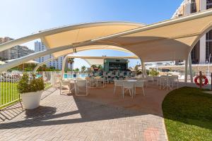 a patio with tables and chairs under a tent at SUNSET WAVES blue sky apartment in Benidorm