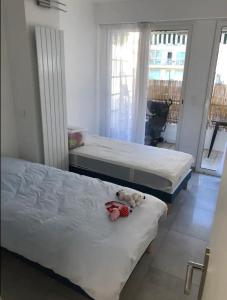 Dos camas en un dormitorio con un osito de peluche. en Impeccable 3 pièces avec balcons à 50m de la plage, en Antibes