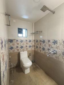 La salle de bains est pourvue de toilettes et de fleurs sur le mur. dans l'établissement Kanvas Suites - Sun N Moon, à Palolem