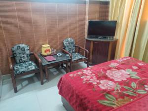 ジャンムーにあるHotel Surya Excellency By WB Innのベッド1台、椅子2脚、テレビが備わる客室です。