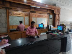 Un uomo in piedi alla scrivania in un barbiere di Hotel Surya Excellency By WB Inn a Jammu