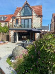 a brick house with an umbrella in a garden at The Breakers in Brancaster