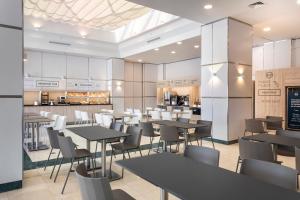 a restaurant with tables and chairs and a counter at B&B HOTEL Madrid Aeropuerto T4 in San Sebastián de los Reyes