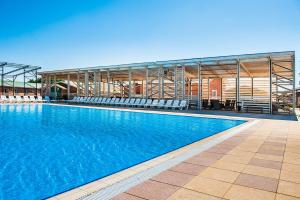a large swimming pool with chairs and a building at Forest resort BalQaragai in Malotimofeyevka