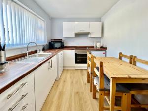 a kitchen with white cabinets and a wooden table at Knick Knack - 10 Minutes Stroll from Brixham Harbour in Brixham