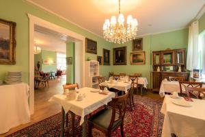 a dining room with tables and chairs and a chandelier at Hotel Villa Raueneck in Bad Saarow