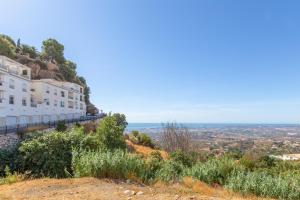 a building on a hill with the ocean in the background at Casa La Puente in Mijas