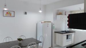 uma cozinha com um frigorífico branco e uma mesa em Casa em Imbassai em Imbassaí