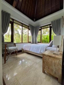 a bedroom with a bed and some windows at Balian Bliss Retreat Bungalow & Villas in Balian