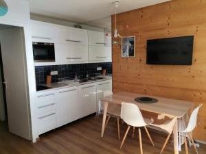 een keuken met witte kasten en een houten muur bij Studio Face au Mont-Blanc in Chamonix-Mont-Blanc