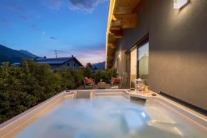 a hot tub on the balcony of a house at Arbulé Agriturismo & Spa Valtellina in Poggiridenti