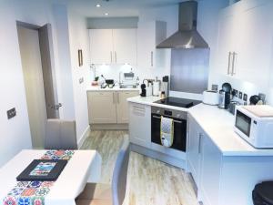 a kitchen with white cabinets and a stove top oven at Gild House 2-bedroom apartment close to Town Centre in Bournemouth