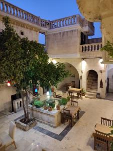 une cour avec des tables et un arbre dans un bâtiment dans l'établissement JOSELİN HOTEL, à Şanlıurfa