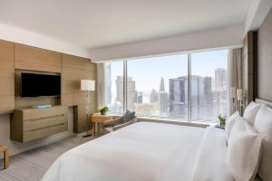Pullman Doha West Bay في الدوحة: غرفة فندقية بسرير كبير ونافذة كبيرة