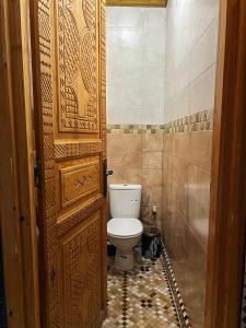 a bathroom with a toilet and a wooden door at Dar Rehab in Rabat
