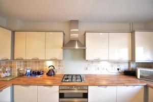 a kitchen with white cabinets and a wooden counter top at Pebble House (Goring-by-Sea) in Worthing