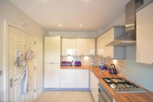 a kitchen with white cabinets and a stove at Pebble House (Goring-by-Sea) in Worthing