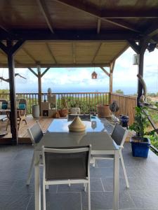 een tafel en stoelen op een patio met een dak bij Maison vue sur la mer Jardin d Orient in Saint-Claude