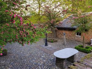 een stenen patio met een tafel en een aantal roze bloemen bij Meschermolen 2 in Eijsden