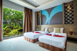 two beds in a room with a window at Areeka Resort Phuket in Thalang