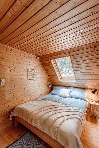 a bed in a wooden room with a window at Kispatak Vendégház in Zebegény