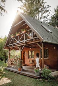 a woman walking into a small wooden house at Kispatak Vendégház in Zebegény