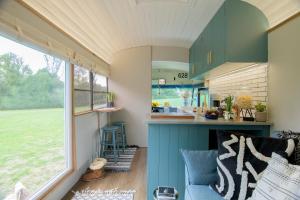 eine Küche mit blauer Insel in einem winzigen Haus in der Unterkunft American School Bus Retreat with Hot Tub in Sussex Meadow in Uckfield