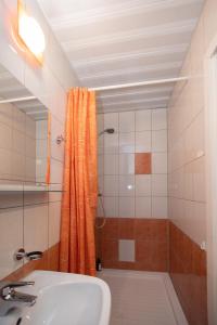 a bathroom with an orange shower curtain and a sink at Revalia Airport-Bus Station One-Bedroom Apartment in Tallinn