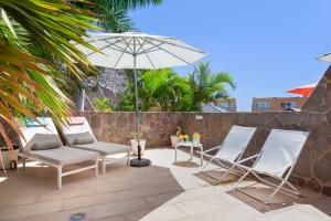 een groep stoelen en een parasol op een patio bij Zen Home Tauro in La Playa de Tauro