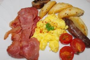 un plato de desayuno con huevos, salchichas, patatas y tomates en Fynbos Guest House Riversdale, en Riversdale