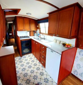 uma cozinha com armários de madeira e um balcão branco em Narrow Escape - 50ft Boat on the Grand Union Canal, near Tring em Tring